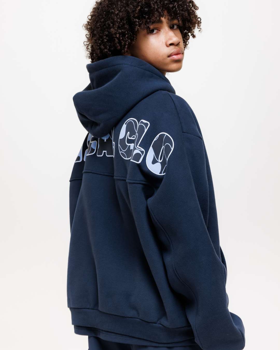 boy wearing next gen navy blue junior hoodie with Rascal camo text design on the back against a white background