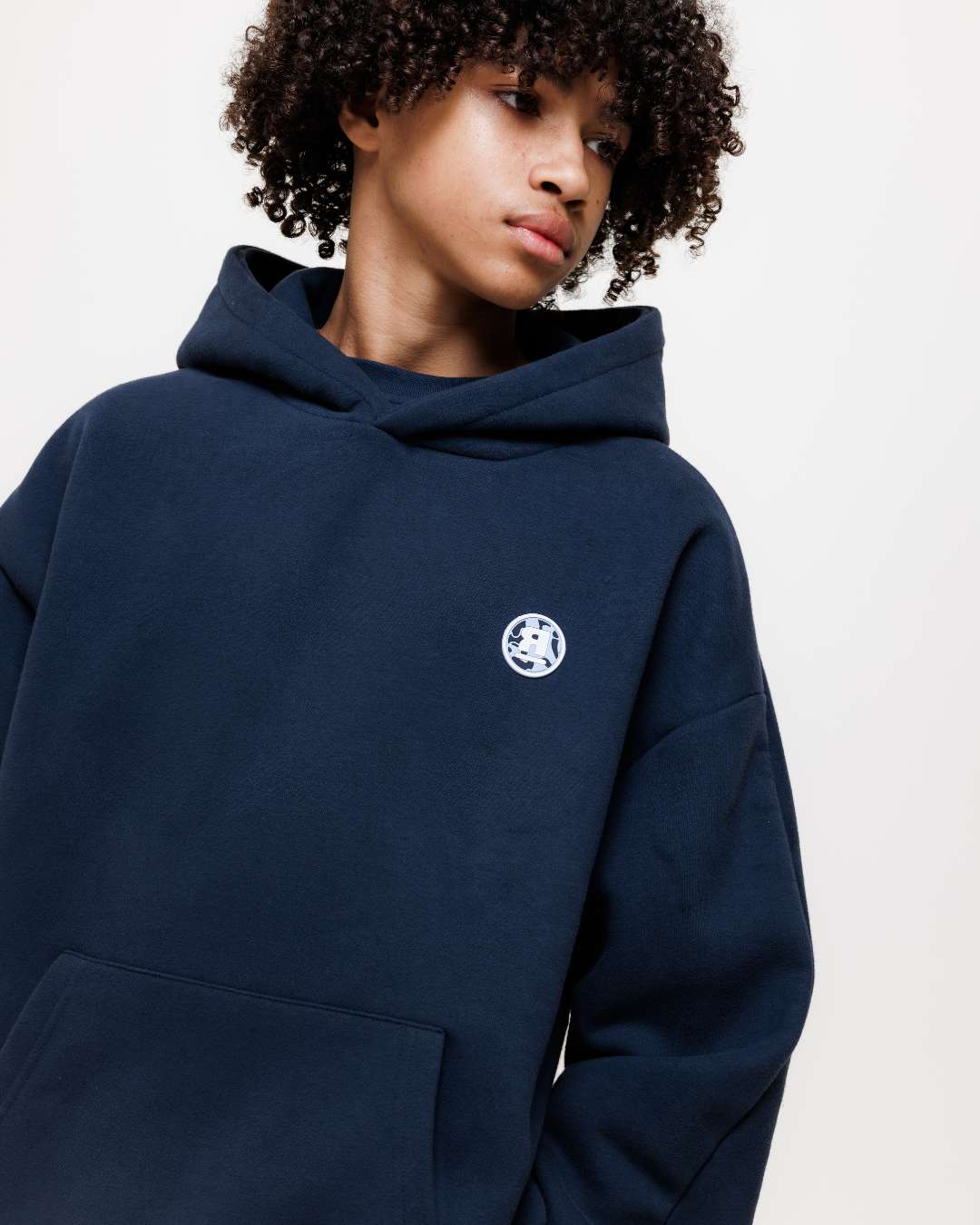 boy wearing next gen navy blue junior hoodie with Rascal camo logo design against a white background