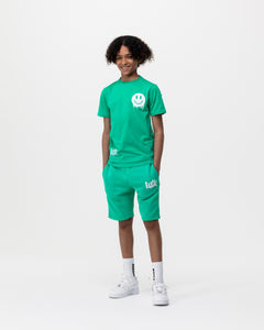 boy standing with hands in pockets wearing green Rascal shorts and Rascal green smiley face tshirt with white Rascal and smiley face graphics