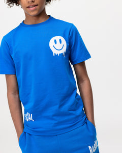 boy wearing Rascal blue shorts and blue smiley tshirt with white Rascal and smiley face graphics with his hands in pockets