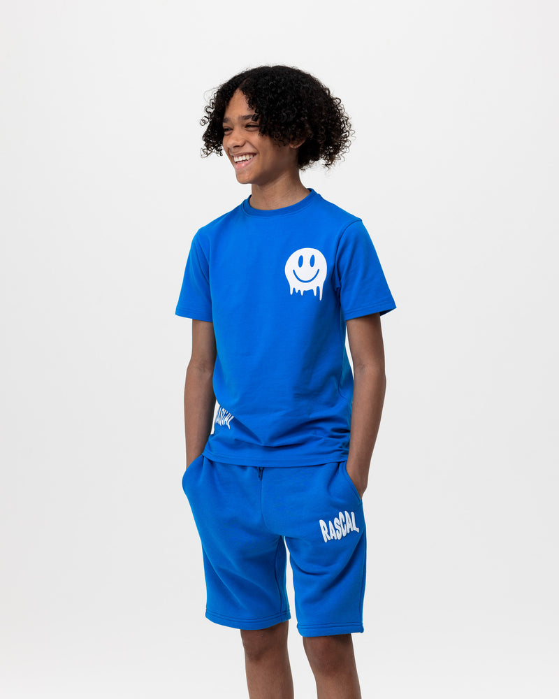 boy with hands in his pockets wearing Rascal blue shorts and blue smiley tshirt with white Rascal and smiley face graphics 