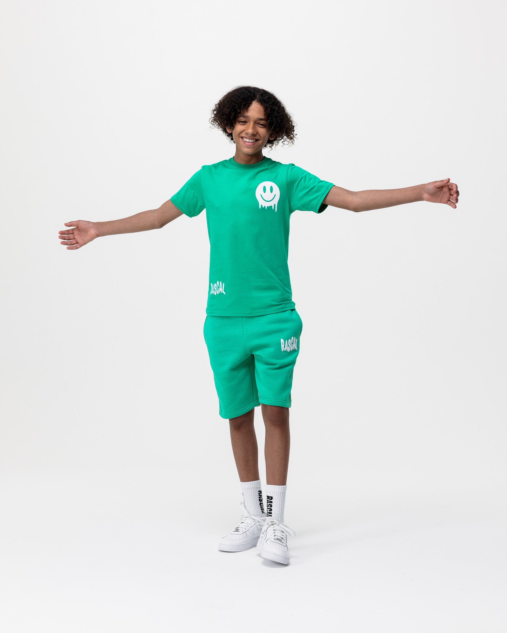 boy standing with hands out wearing Rascal green smiley tshirt and green kids cotton shorts with white Rascal logo graphic