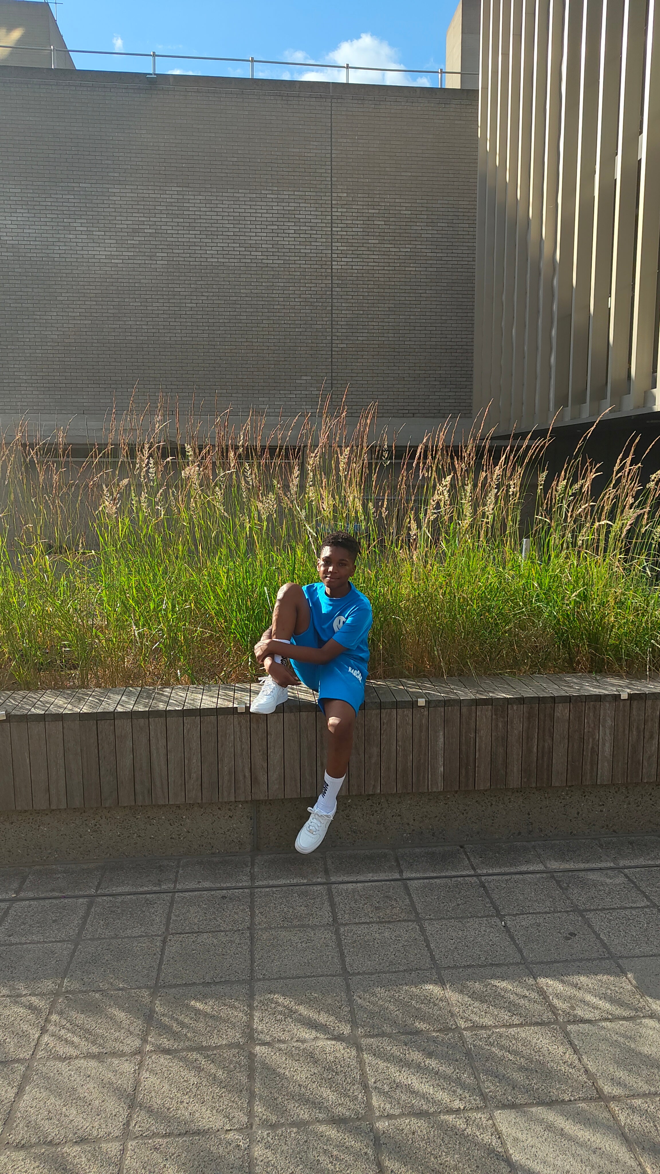 boy sat wearing Rascal blue shorts and blue smiley tshirt