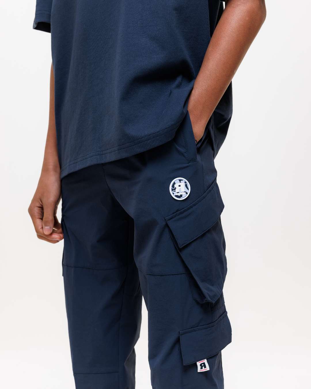 Next Gen junior Navy cargo pants with Rascal designs on a white background