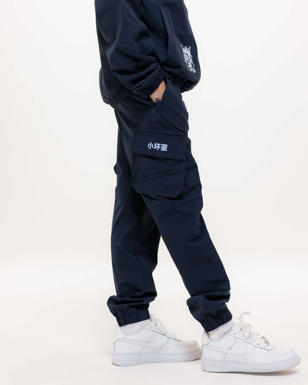 Side view of boy wearing Rascal Next Gen junior navy blue cargos showing pocket with Chinese symbols design 