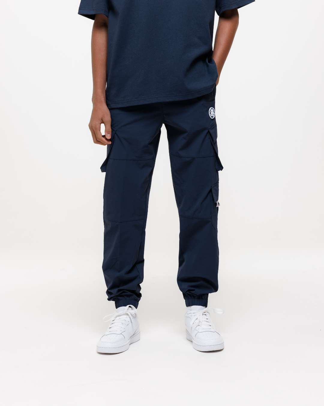 Boy wearing Next Gen junior navy blue cargo pants with Rascal design elements on a white background