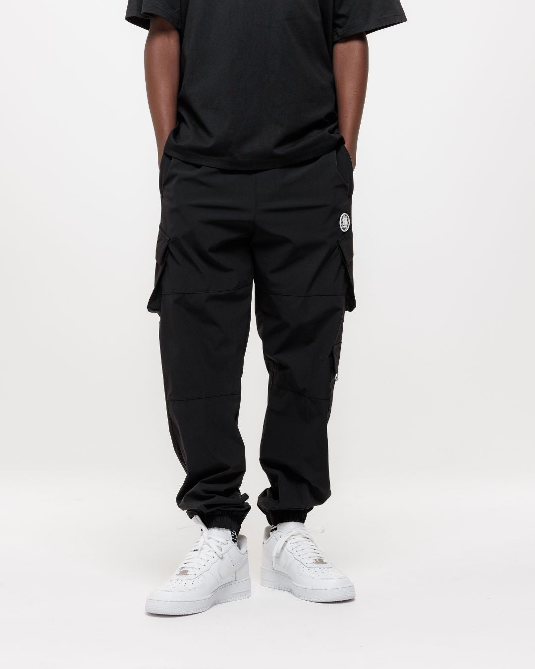 boy wearing next gen black junior cargo pants and tee with Rascal camo logo designs, hands in pockets stood in front of a white background