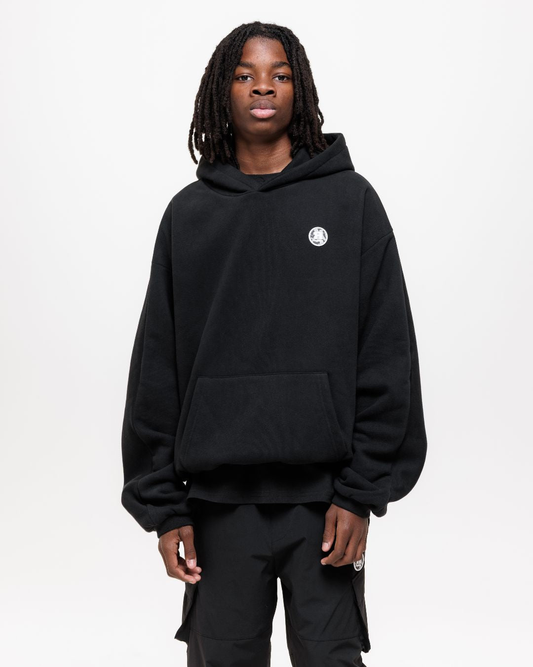 boy wearing next gen black junior oversized hoodie and cargo pants with Rascal camo logo design stood in front of a white background